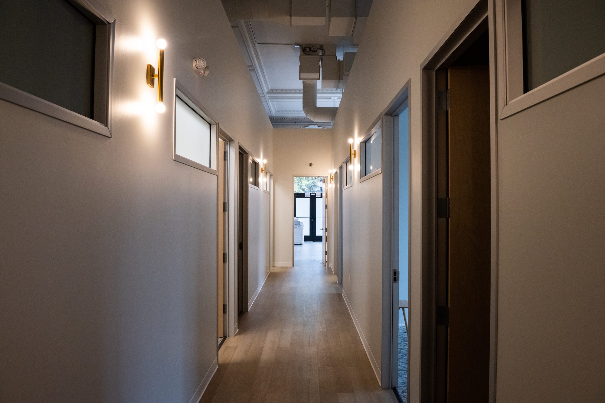 Lower-level corridor with new oak flooring and sconces