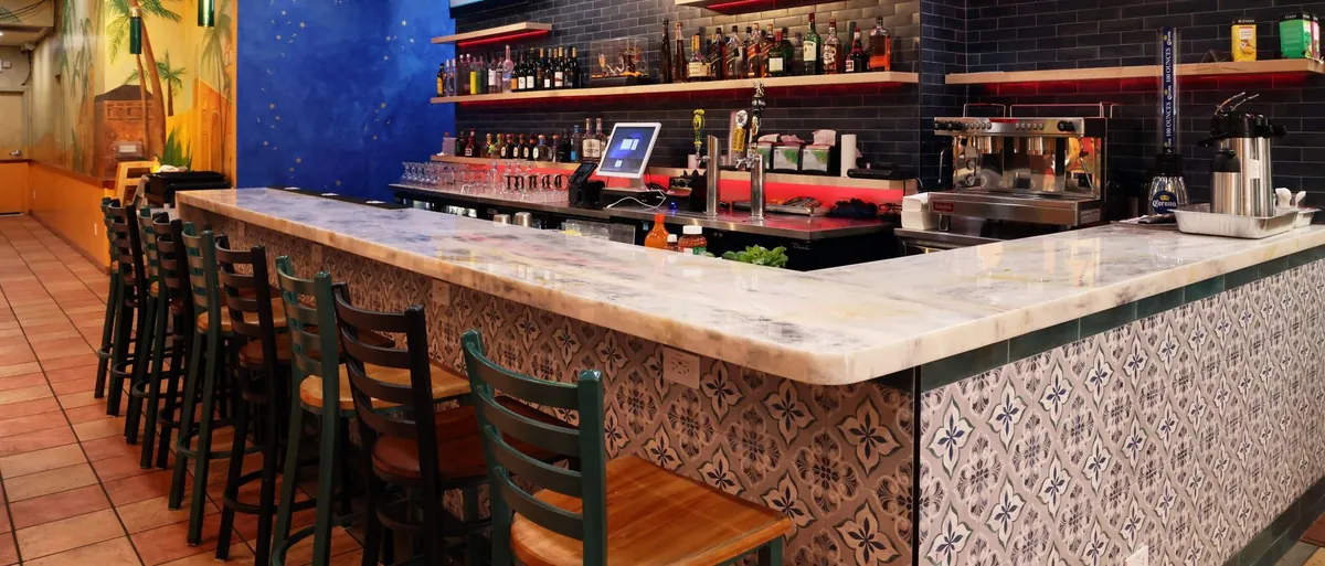 Stone bar top and patterned tile bar front with seating